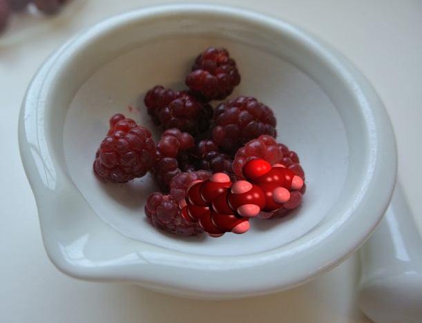 Raspberries and a molecule of raspberry ketone (4-(4-Hydroxyphenyl)butan-2-one) in a mortar, with the pestle lying next to it. 
