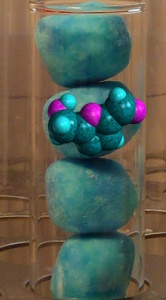 Sweets in a large test tube, together with a molecule of HMF.